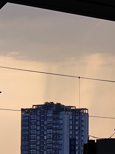 The image shows a tall building with many windows and balconies, set against a backdrop of a cloudy sky at sunset or sunrise. (由 AI 生成标题)