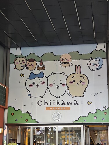 The image is a photo of a large sign featuring cartoon animals and the word "Chiikawa" in front of a building with glass doors and windows. (由 AI 生成标题)
