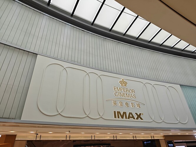 The image shows a sign for Emperor Cinemas, featuring the words "Emperor Cinemas" in gold lettering, accompanied by Chinese characters and the IMAX logo. (由 AI 生成标题)