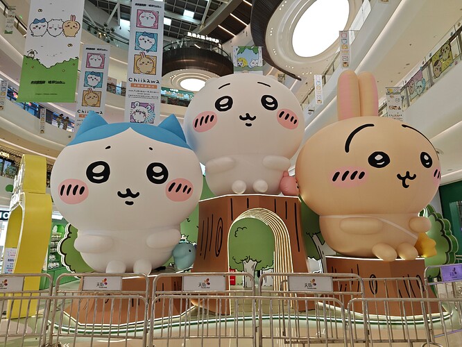 The image shows three large cartoon animal statues, resembling raccoons or bunnies, displayed on a platform in a shopping mall. (由 AI 生成标题)