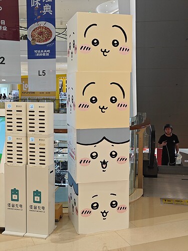 The image depicts four large cardboard boxes stacked on top of each other, each featuring a different cartoon face drawn on it. (由 AI 生成标题)