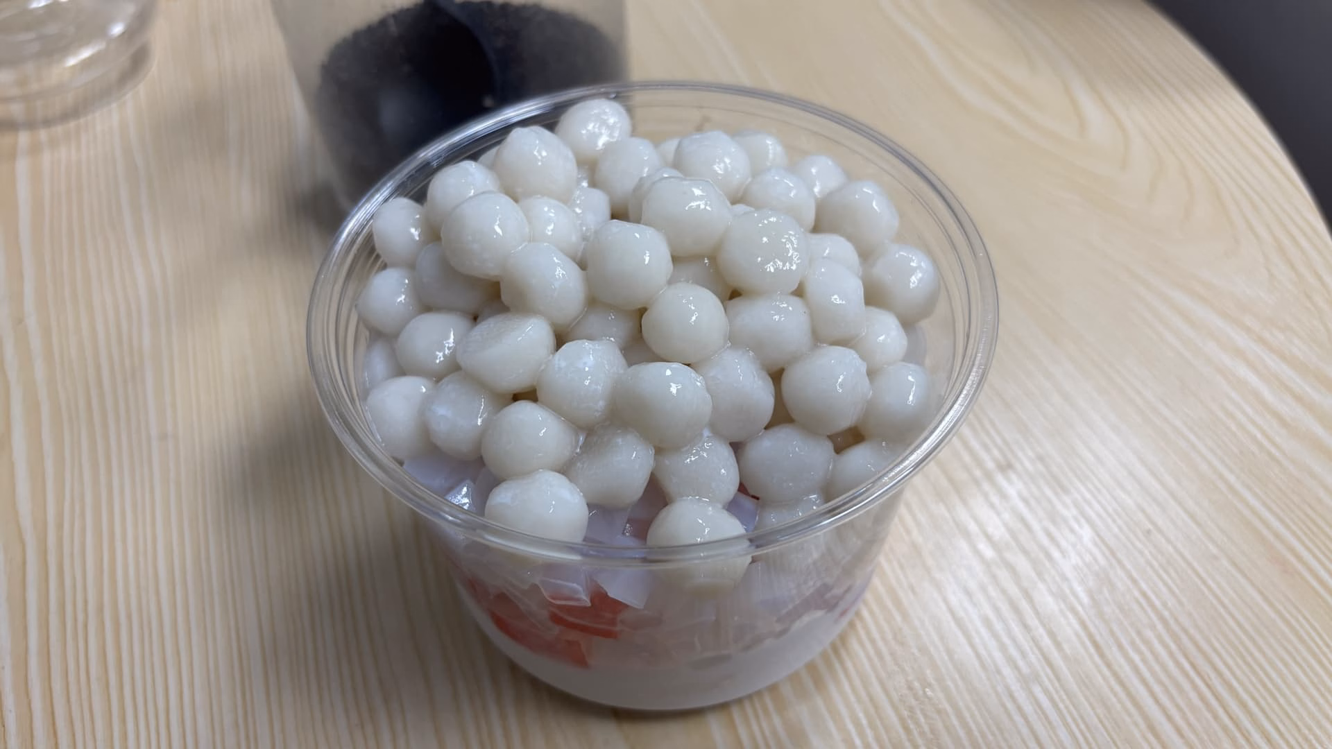 一张近距离的图片展示了一个装满白色汤圆的透明塑料杯。 (由 AI 生成标题)|690x388