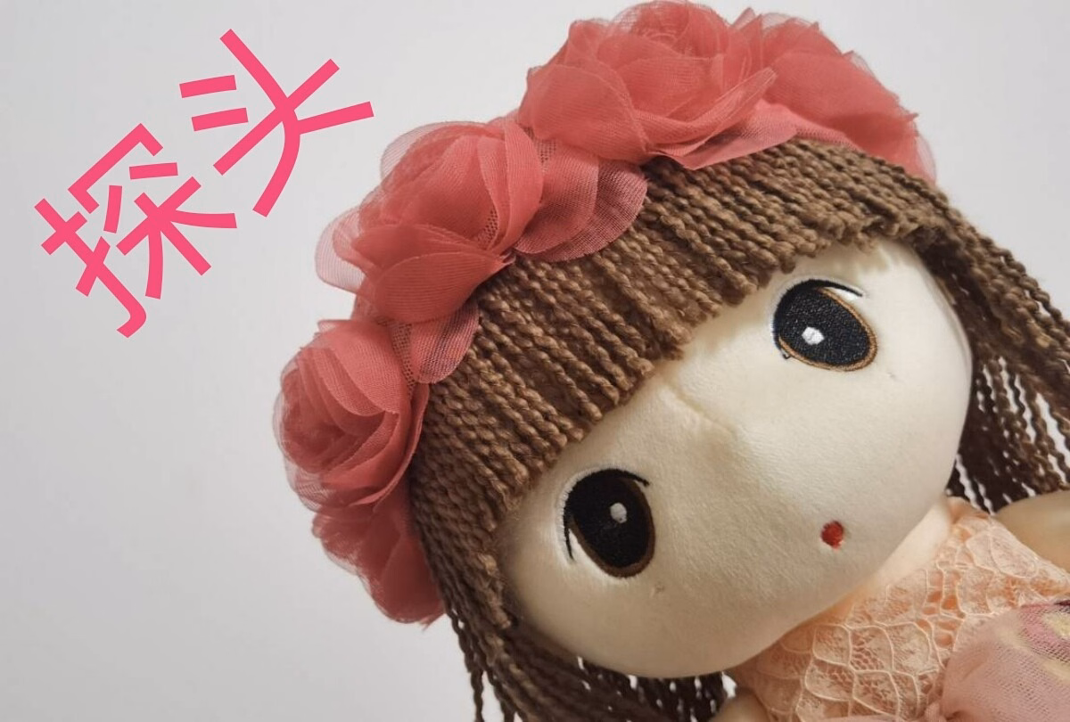 This is an image of a cute, brown-haired doll with a pink flower in her hair, wearing a brown wig, and it has pink Chinese characters in the background.  (Captioned by AI)|690x465